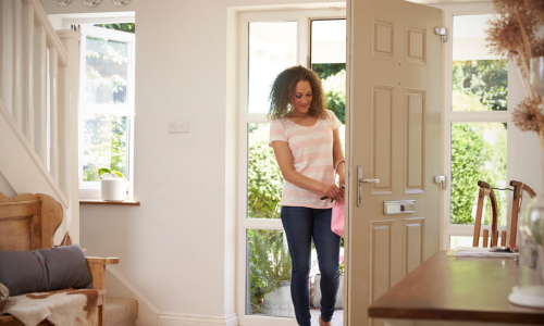 A woman opening her front door with keys.