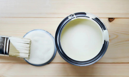 An open paint can next to a paint brush.